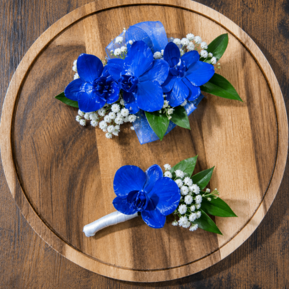 Blue Homecoming corsage and boutonniere with white flowers and school-spirit ribbon.